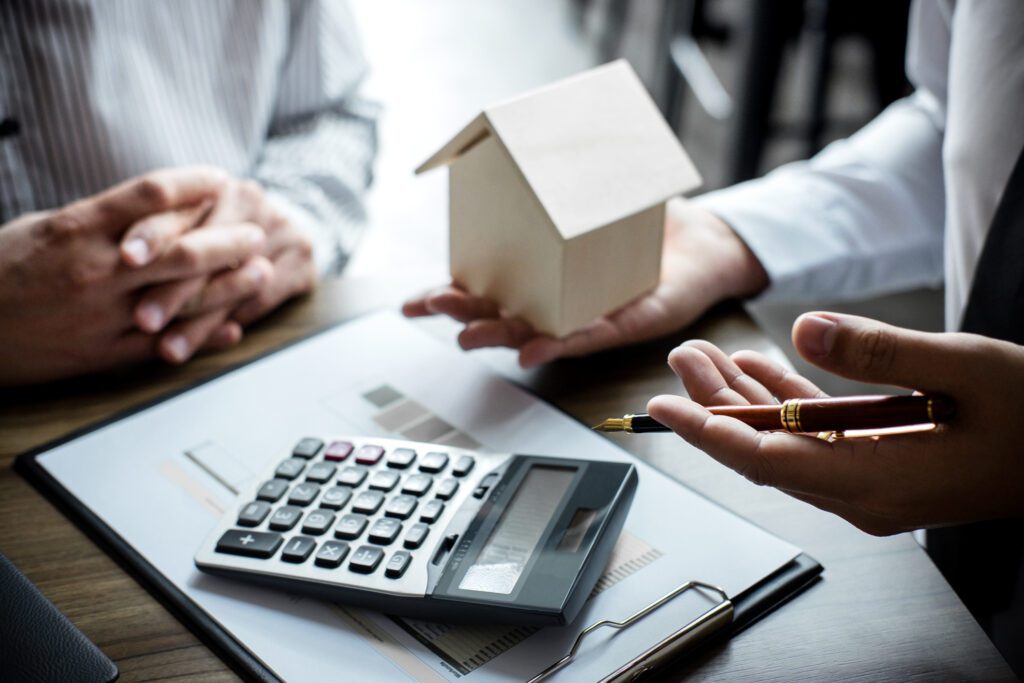 Close up of hands holding a miniature house and pen